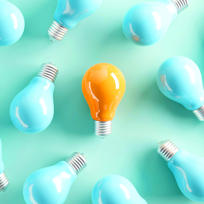 A yellow light bulb surrounded by aqua light bulbs on an aqua background, standing out like designing a new brand