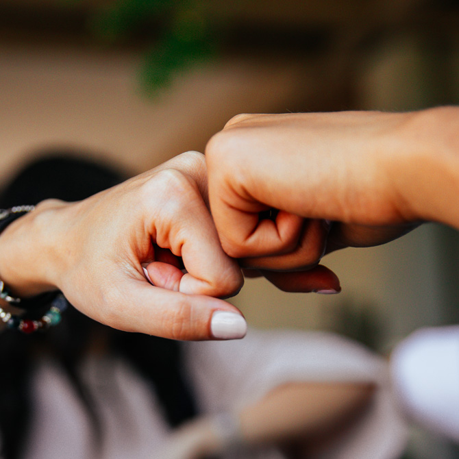 An in-person fist bump, showing that Bourn Creative works with clients remotely and in person