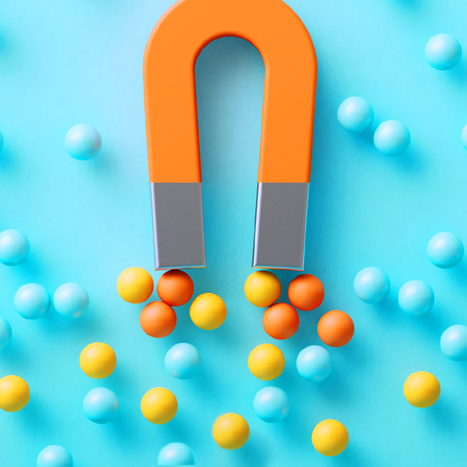 A bright orange magnet pulling yellow and orange balls toward it just as a strong brand pulls clients and customers into its brand world