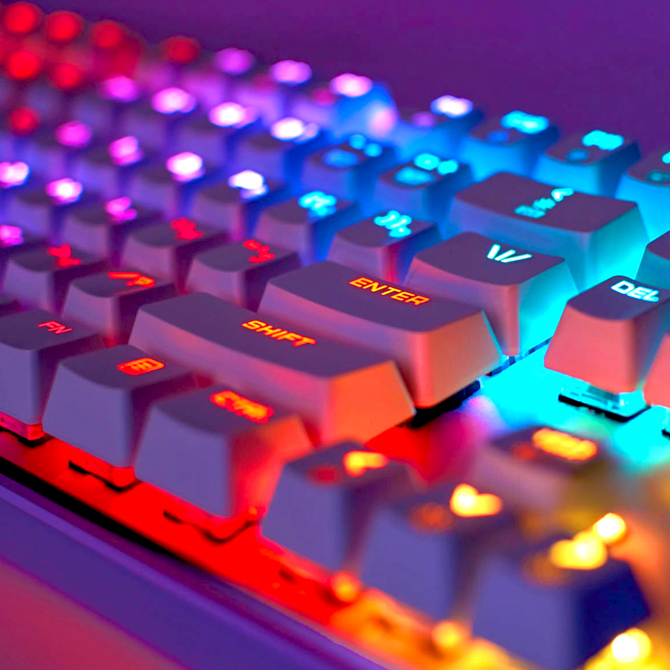 A web designer's keyboard lit with yellow, orange, pink, turquoise, and purple rainbow lights