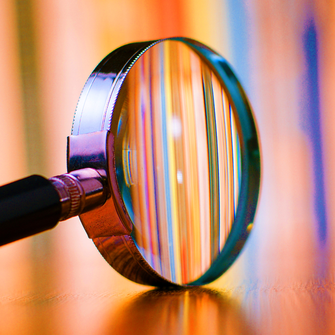 A magnifying glass clarifying the colorful files and data behind it to represent search engine optimization and AI visibility