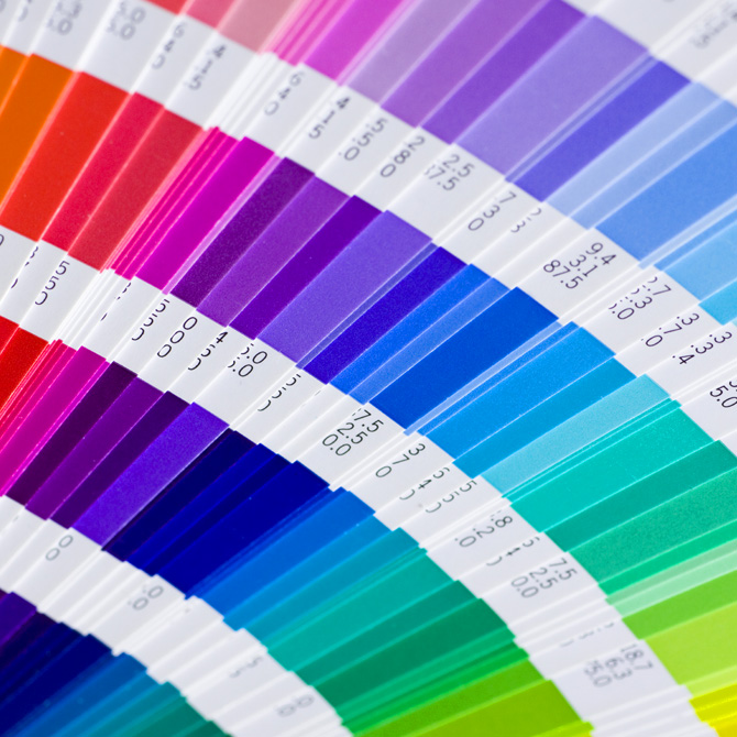 A closeup of a graphic designer's Pantone color swatch formula guide, with the pages fanned out, so a client can see the colors during the visual brand design and color palette selection process