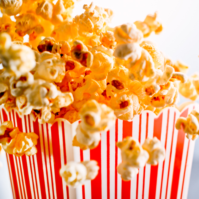 A square red and white striped popcorn bucket overflowing with buttery popcorn, ready for a future client about to read a compelling project case study