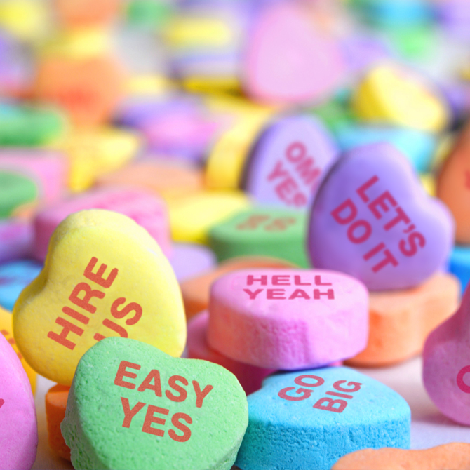Bright colored conversation hearts candies with saying that confirm agency fit, like easy yes, hire us, hell yeah, and let's do it