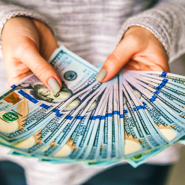 A woman holding a stack of $100 bills fanned out in front of her, showing off the revenue her content marketing generated